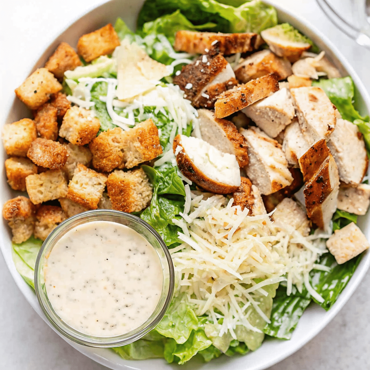 grilled-chicken-caesar-salad-featured.png grilled chicken caesar salad in a rustic bowl with dressing