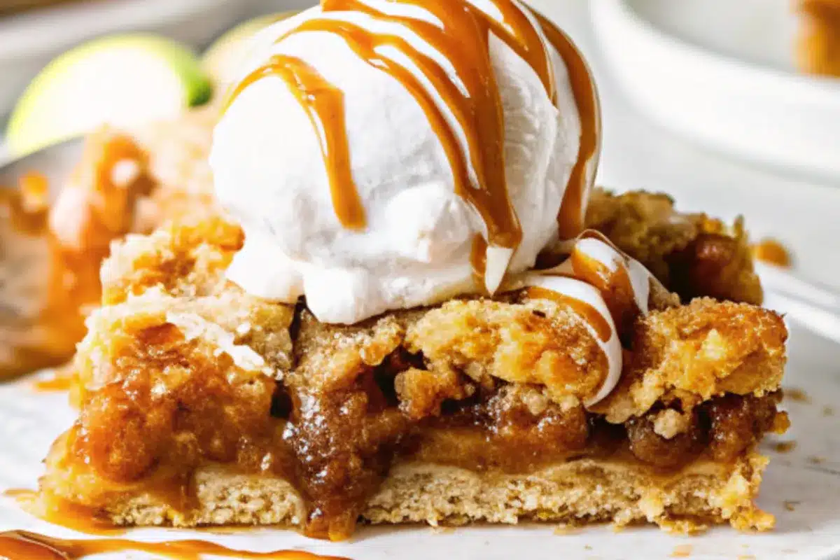 Golden brown salted caramel apple crumb bars cut into perfect squares on white parchment paper, showing layers of buttery crumb topping and tender apple filling