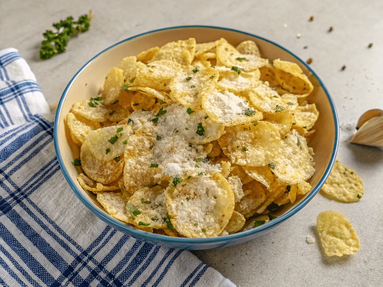 Hand holding Garlic Butter Chips with herbs.